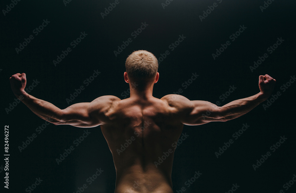 muscular young man showing his biceps isolated on black muscular young man showing his biceps isolated on black