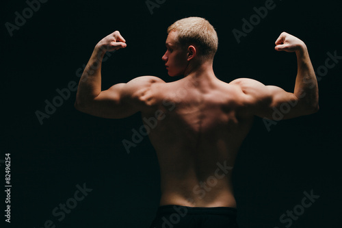 muscular young man showing his biceps isolated on black