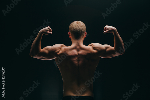 muscular young man showing his biceps isolated on black