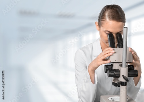 Microscope. Female researcher looking through microscope