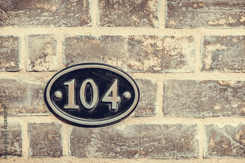 House number one hundred and four engraved in a black metal plat House number one hundred and four engraved in a black metal plat
