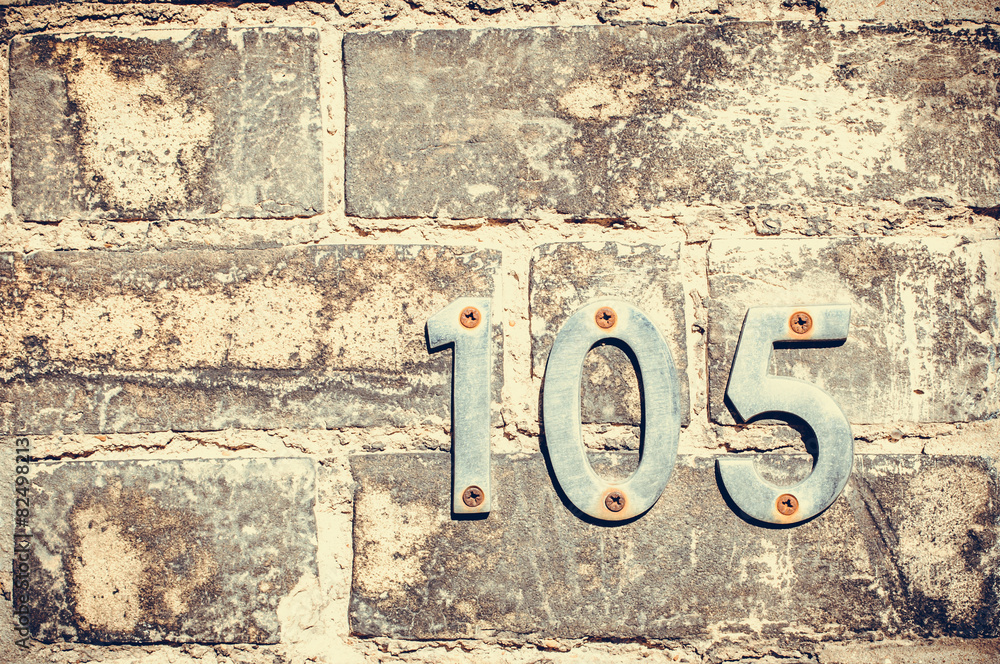 House number one hundred and five on a brick wall