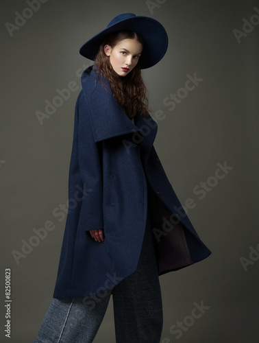 fashion model woman coat and hat urban style pose on color