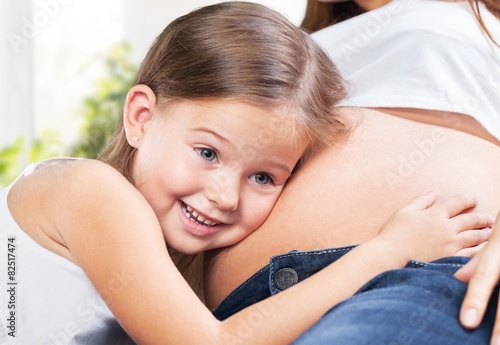 Abdomen. Happy kid girl hugging pregnant mother's belly