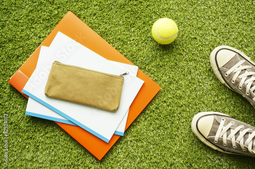 Sneakers, notebooks, pencase and tennis ball on the lawn photo