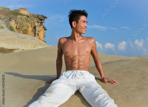 male fitness model in exercise sitting outdoors.