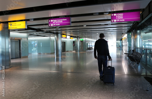 Man with suitcase at an airport lobby.