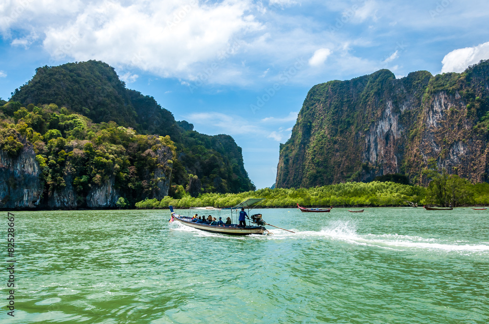 Fototapeta premium Longtail boat passing by with passengers on board