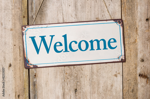 Old metal sign in front of a rustic wooden wall - Welcome