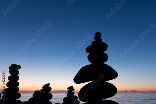 Ocean sunset   evening sun at beach with stacked stone pyramid