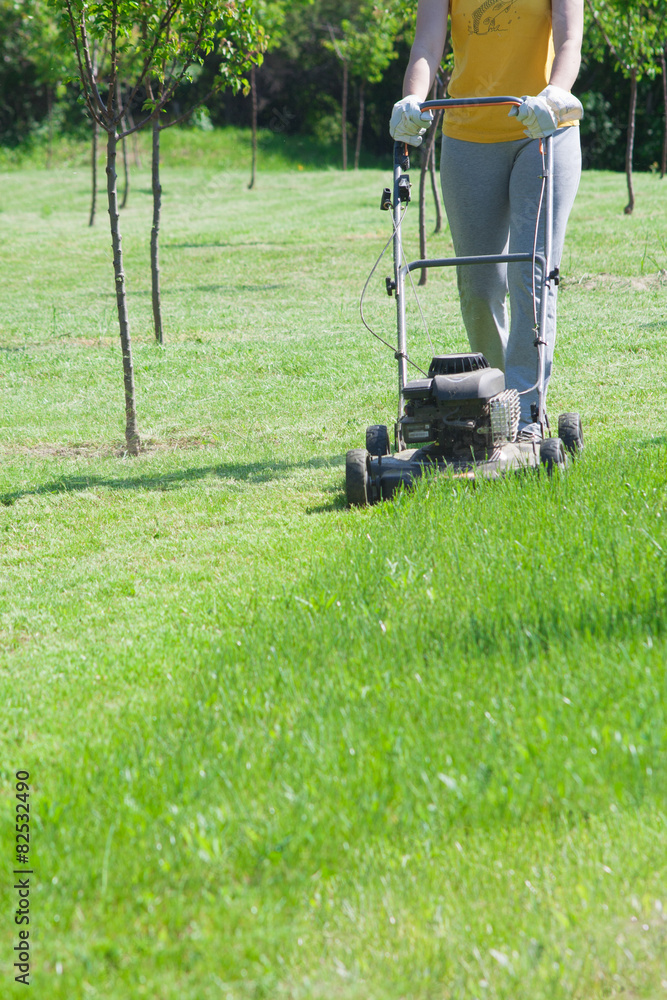 Young female in yard - pushing grass trimming lawnmower Young female in yard - pushing grass trimming lawnmower