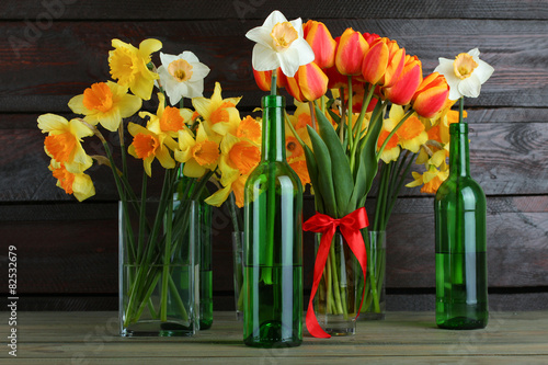 Fototapeta Naklejka Na Ścianę i Meble -  Daffodils and tulips in a glass vase on a wooden background