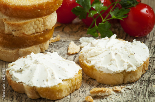 Home crostini with soft cheese and tomatoes on a wooden table, s photo