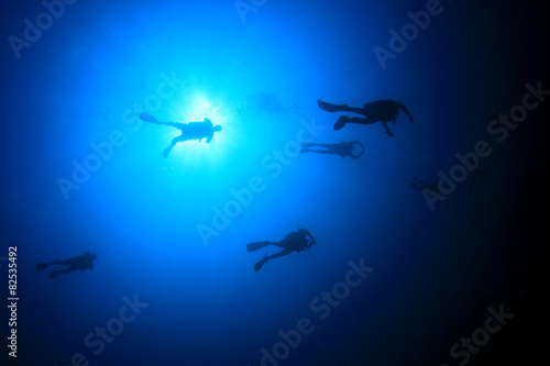 Scuba diving underwater  divers silhouette and sun
