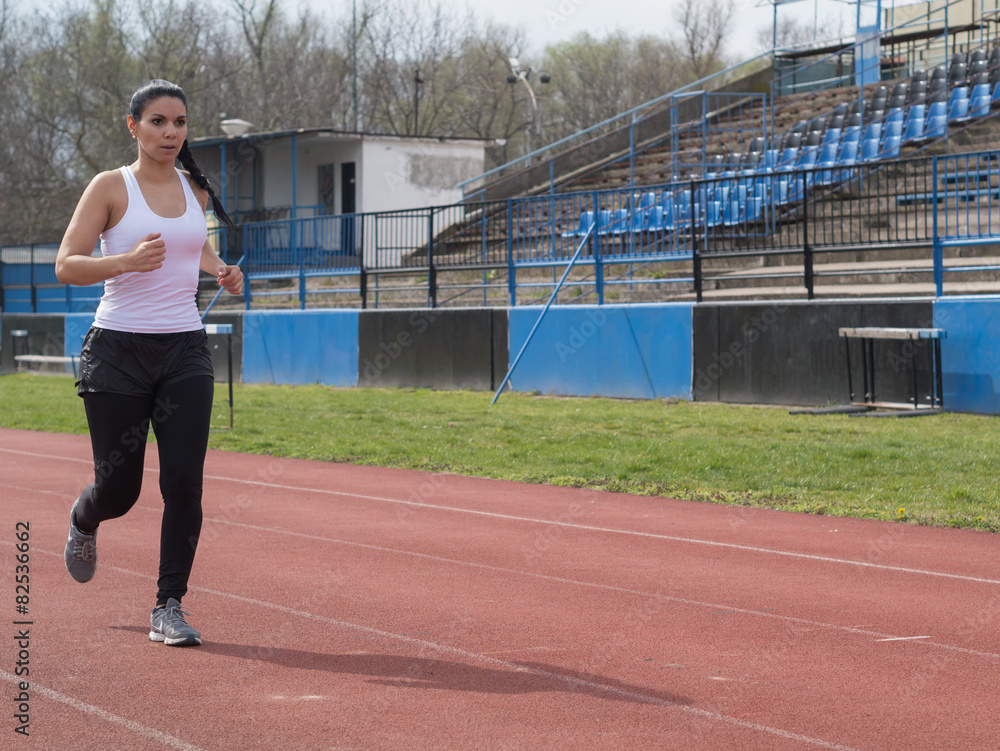 Fototapeta premium Shapely woman in white tights running in the sports facility