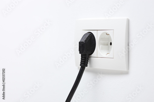 Black electric cord plugged into a socket