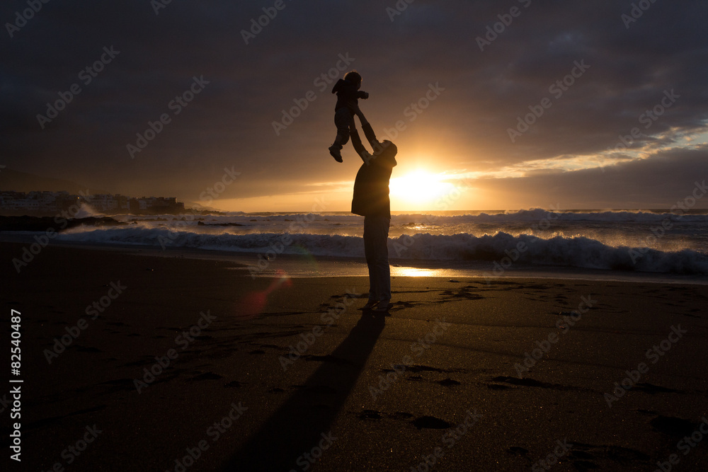 father holding child - family silhouette - beach sunset