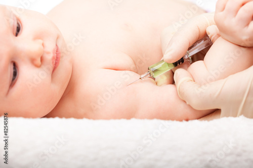 Pediatrician giving baby girl intramuscular injection in arm