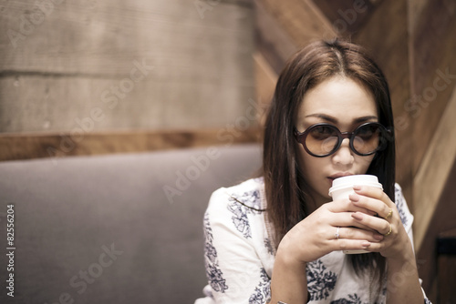Fototapeta Naklejka Na Ścianę i Meble -  Asian woman  drinking coffee in a cafe