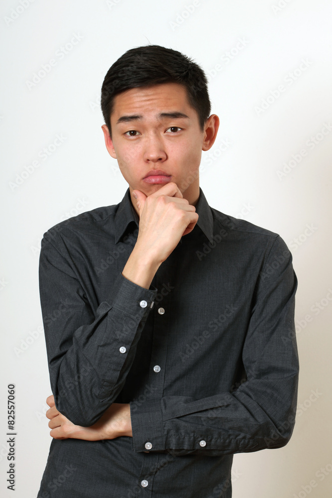 Thinking young Asian man looking at camera Thinking young Asian man looking at camera