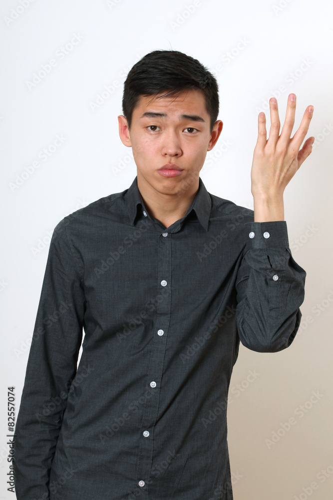 Frustrated young Asian man gesturing with his hand Frustrated young Asian man gesturing with his hand