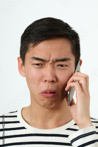 Disgusted young Asian man using a smartphone