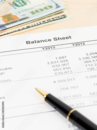 Balance sheet financial report with pen, and banknote