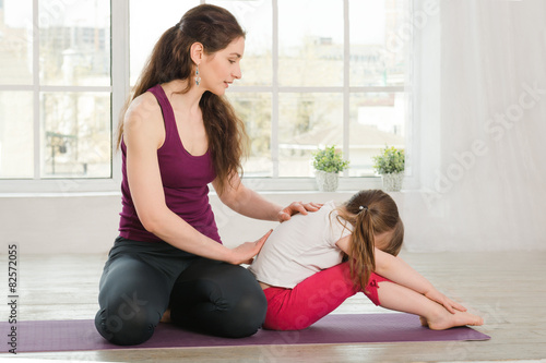 Young mother comforting daughter during yoga exercise