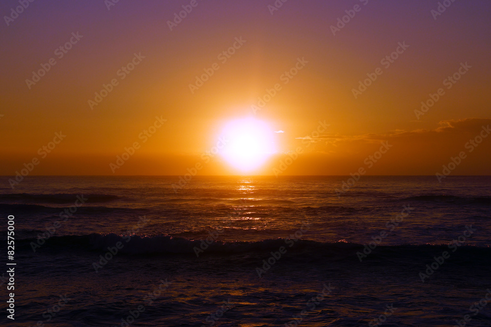 Sunrise over the ocean with waves rolling toward shore