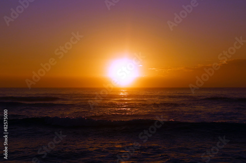 Sunrise over the ocean with waves rolling toward shore