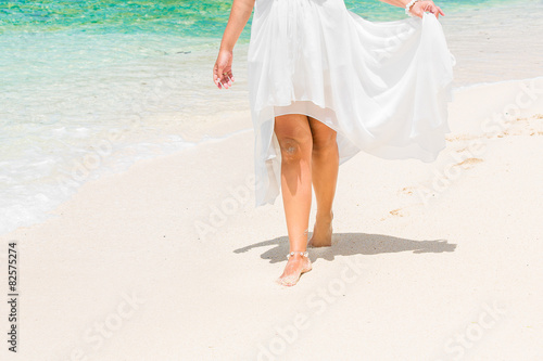 beautiful young bride in a white wedding dress walking on a trop