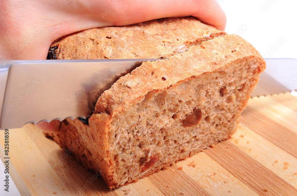 Hand of woman slicing fresh baked bread