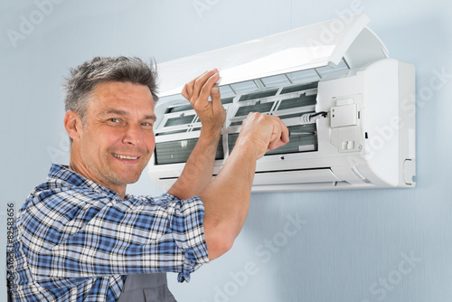 Schilderij op canvas Male Technician Repairing Air Conditioner