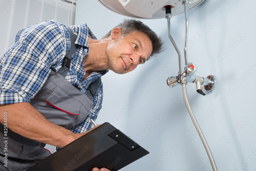 Obraz premium Plumber With Clipboard Looking At Electric Boiler