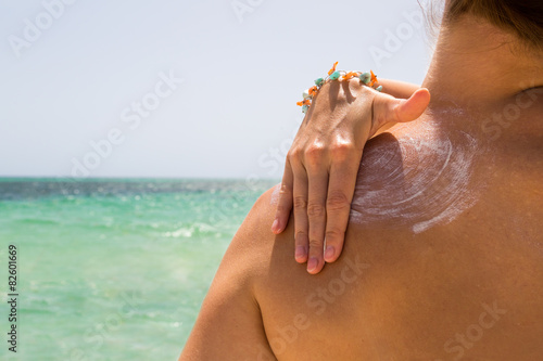 Sonnencreme auf der Schulter verteilen