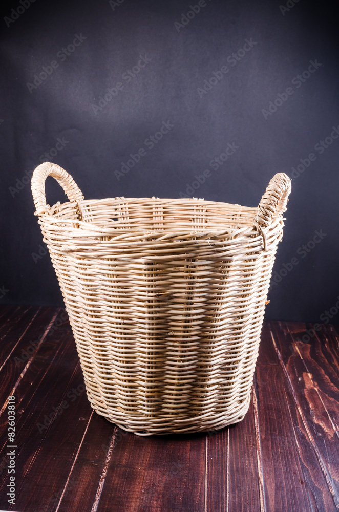Empty wicker basket on wooden board Empty wicker basket on wooden board