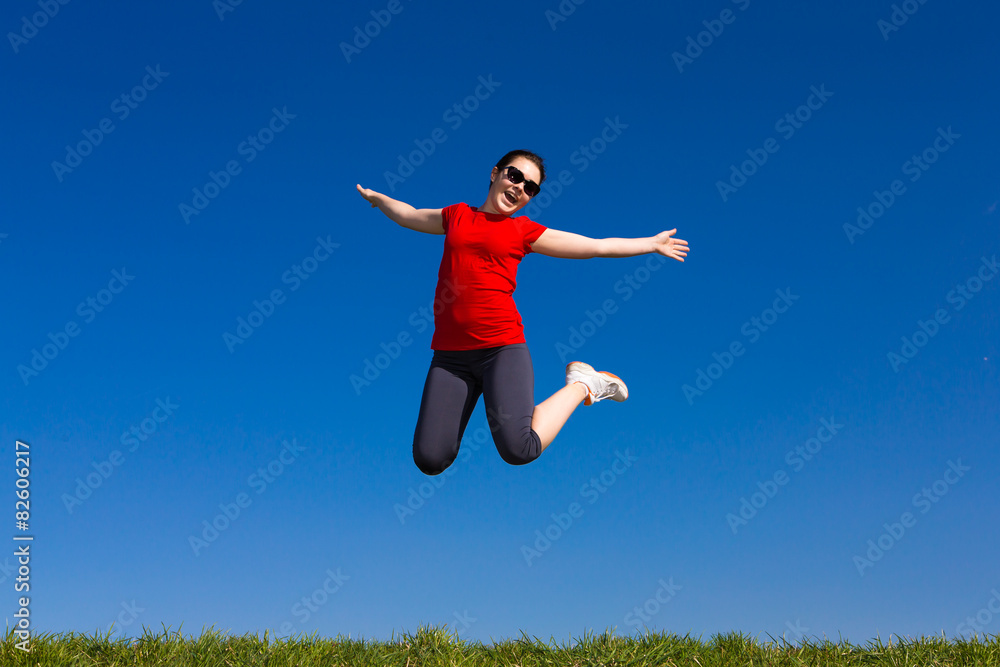 Teenage girl jumping, running outdoor against blue sky