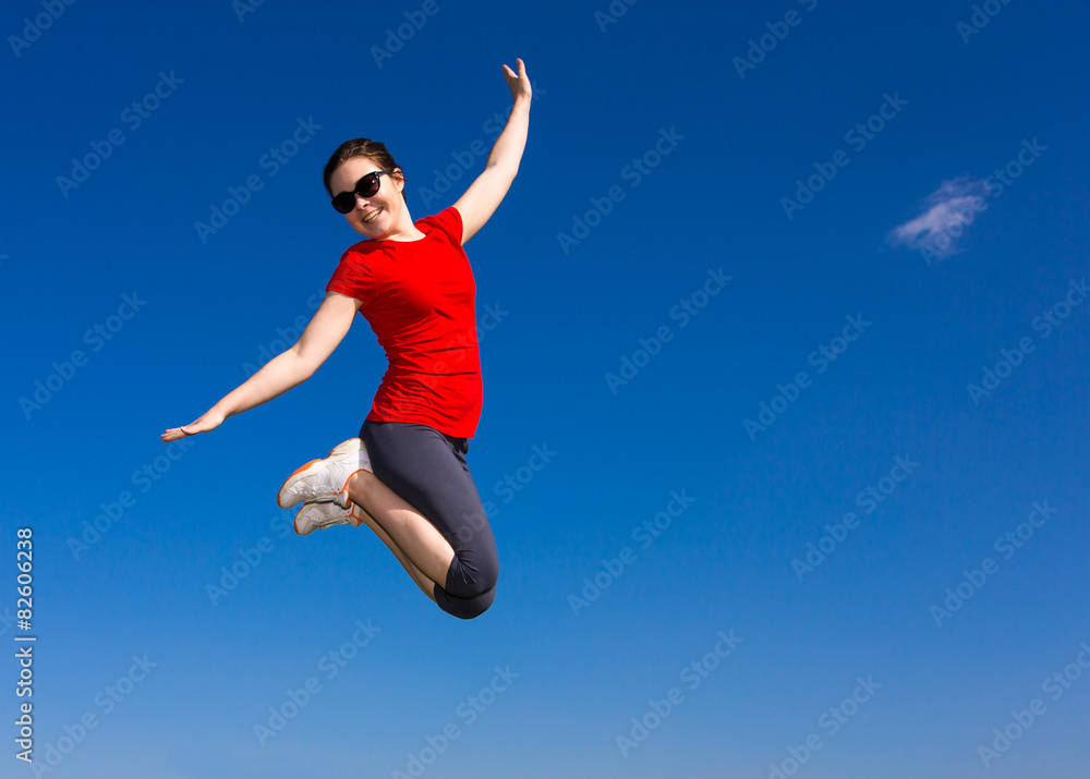 Teenage girl jumping, running outdoor against blue sky