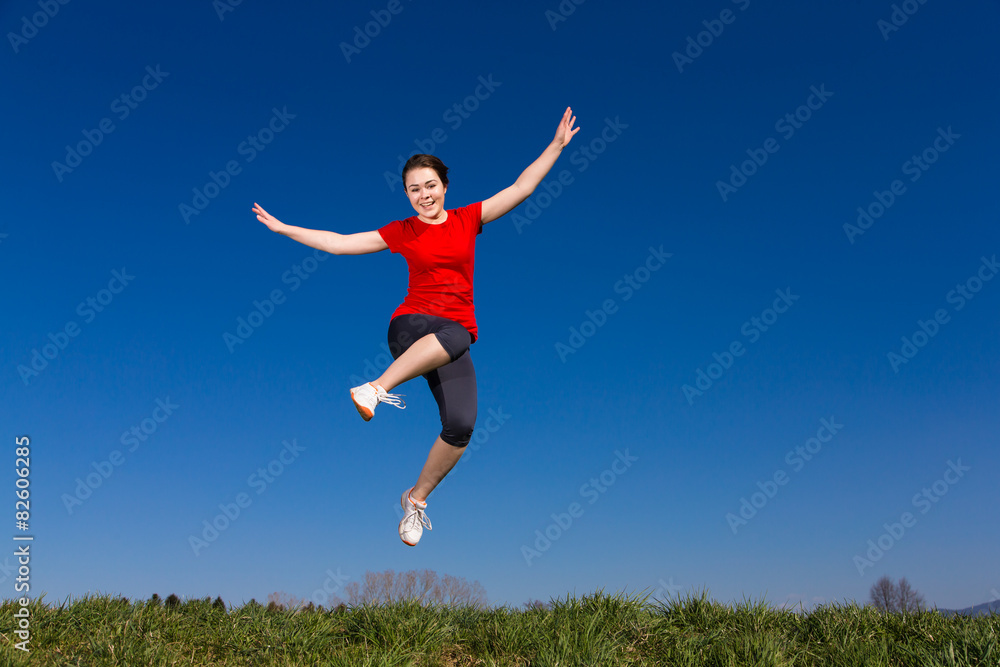 Teenage girl jumping, running outdoor against blue sky