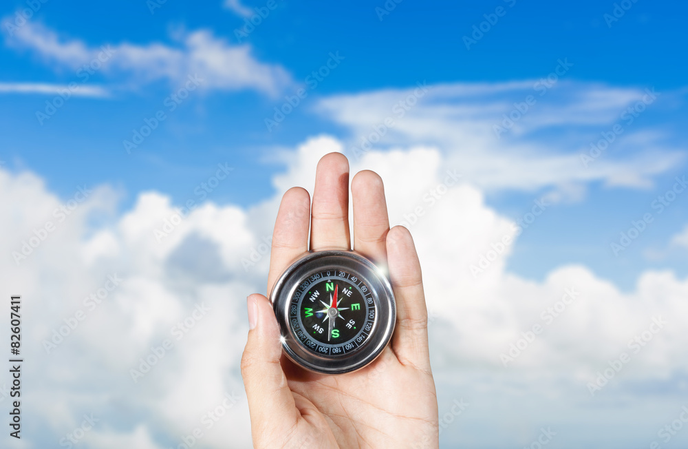 The hand of a man holding a compass over a landscape view