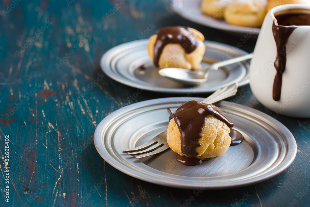 profiteroles with cream and chocolate sauce on dark blue backgro profiteroles with cream and chocolate sauce on dark blue backgro