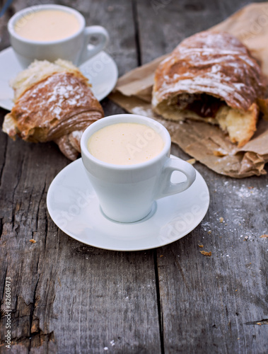 A cup of coffee "espresso" and croissant on the wooden table. 