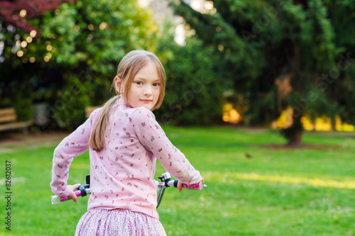 Little sweet girl on her bycicle in a park 
