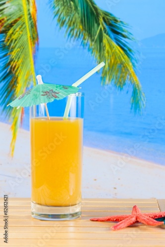 glass of orange juice on the sandy beach near starfish © donfiore