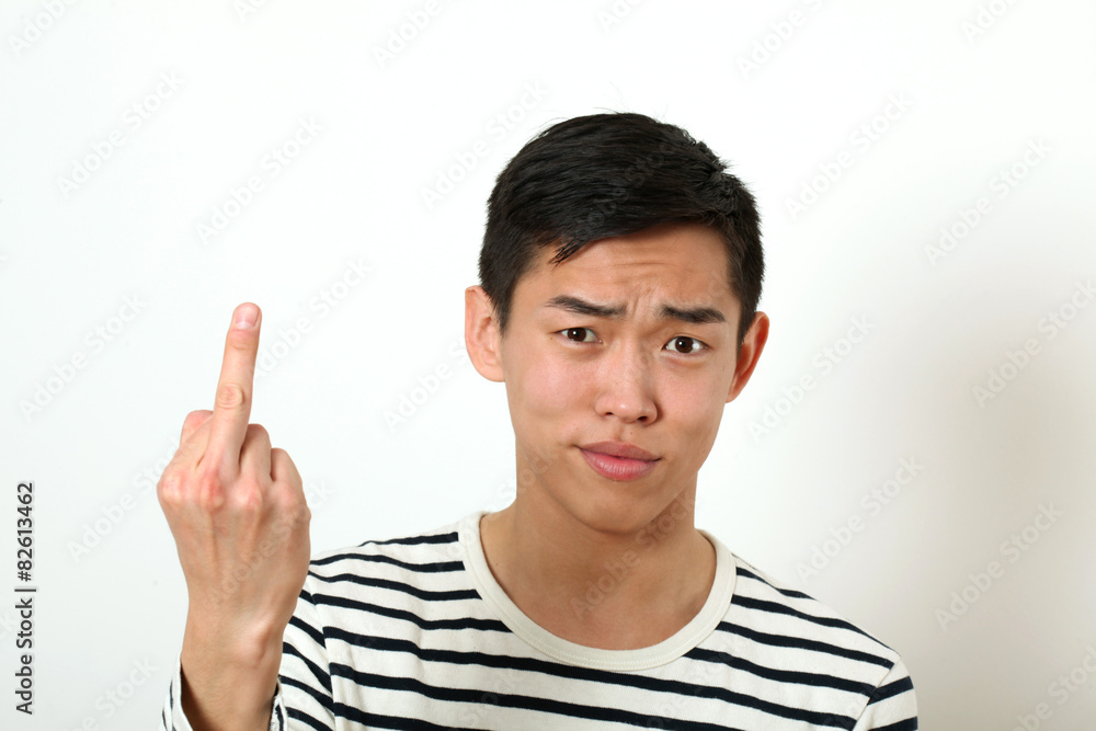 Displeased young Asian man giving the middle finger sign and loo Displeased young Asian man giving the middle finger sign and loo