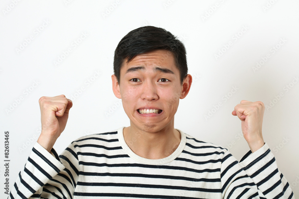 Displeased young Asian man shaking two fists Displeased young Asian man shaking two fists