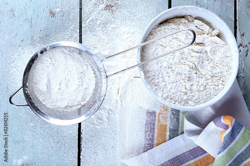 Photos Sifting flour through sieve on wooden table, top view