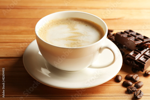 Cup of coffee latte art with grain and chocolate on wooden background © Africa Studio