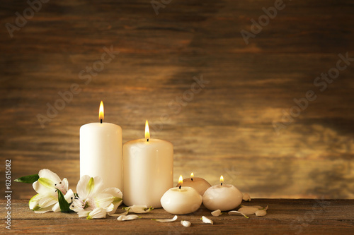 Candles with flowers on wooden background