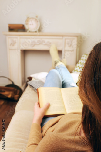 Woman reading book on sofa in room
